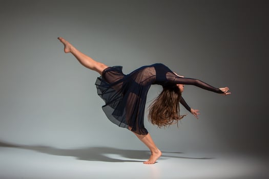 Young beautiful dancer in black dress posing on a dark gray studio background photo