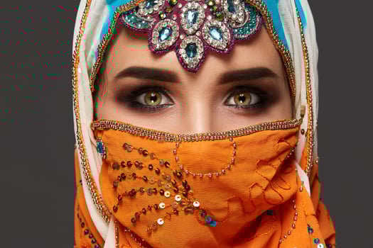 Studio shot of a chrming female wearing the colorful hijab decorated with sequins and jewelry. Arabic style. photo