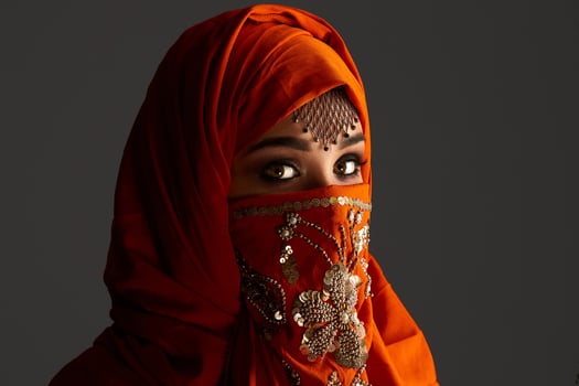 Studio shot of a young charming woman wearing the terracotta hijab decorated with sequins and jewelry. Arabic style. photo