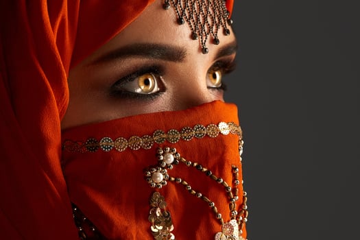 Studio shot of a young charming woman wearing the terracotta hijab decorated with sequins and jewelry. Arabic style. photo