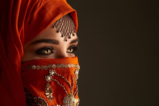 Studio shot of a young charming woman wearing the terracotta hijab decorated with sequins and jewelry. Arabic style. photo