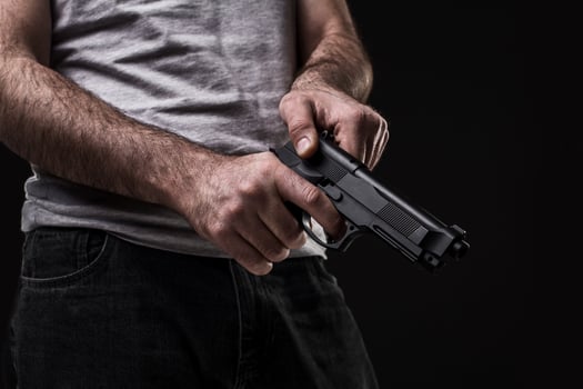 Killer with gun on black background at the studio photo