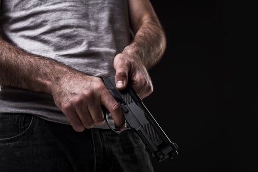 Killer with gun on black background at the studio photo