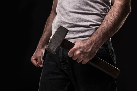 Male offender with a big hammer. On black background at the studio photo