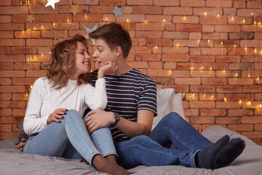 Young man and woman tenderly embracing in bedroom on the bed photo