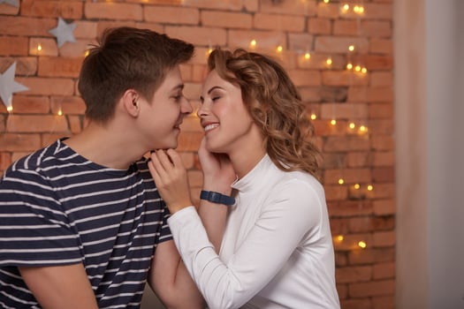 Happy loving couple relaxing on bed at home, young man touching smiling beautiful woman face, looking in the eyes. photo