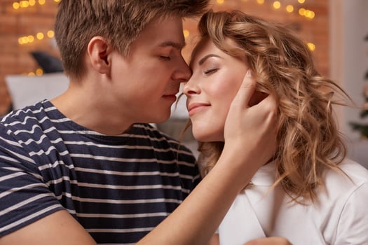 Close up portrait of a beautiful couple sitting on the floor embracing and looking to each other photo