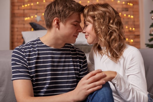 Close up portrait of a beautiful couple sitting on the floor embracing and looking to each other photo