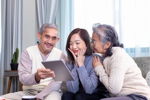 Asian family reunion of senior father mother and daughter sitting on couch with happy smile in retirement home while looking at the old nostalgic photo in the past