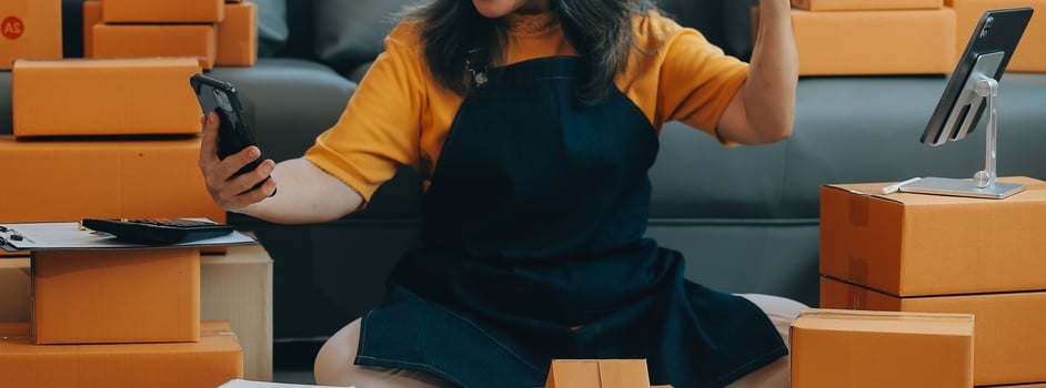 Startup SME small business entrepreneur of freelance Asian woman wearing apron using laptop and box to receive and review orders online to prepare to pack sell to customers, online sme business ideas. photo