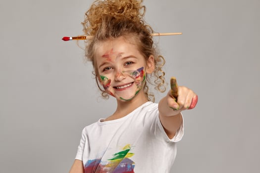 Beautiful little girl with a painted fingers is posing on a gray background. photo