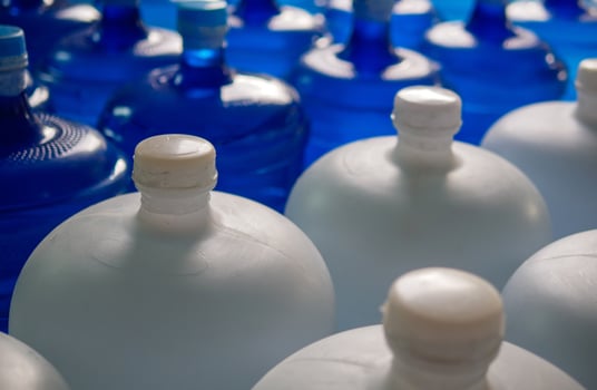 plastic big bottles or white and blue gallons of purified drinking water inside the production line. Water drink factory photo