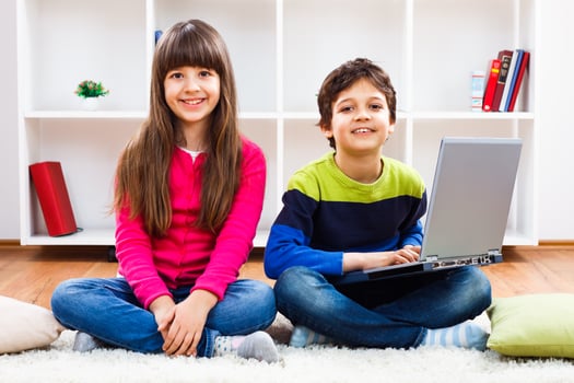 Two children sitting on the floor with a laptop photo