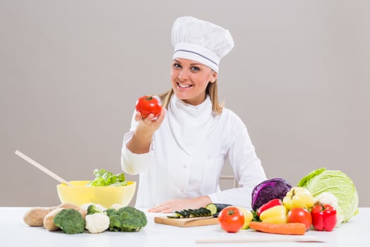 Female chef showing tomato while making healthy meal photo