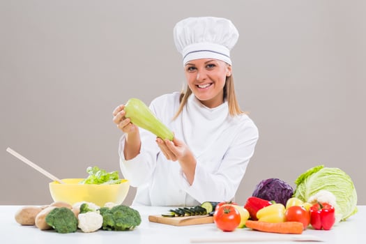 Female chef showing zucchini while making healthy meal photo