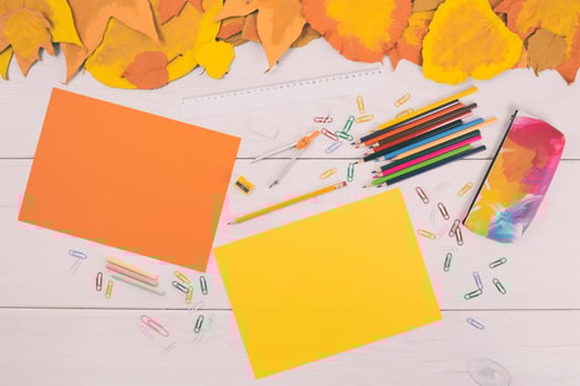 Autumn leaves and school supplies on white wooden table top view photo