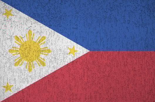 Philippines flag depicted in bright paint colors on old relief plastering wall. Textured banner on rough background photo