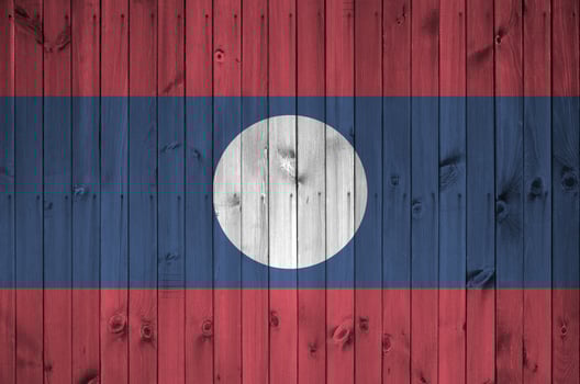 Laos flag depicted in bright paint colors on old wooden wall. Textured banner on rough background photo