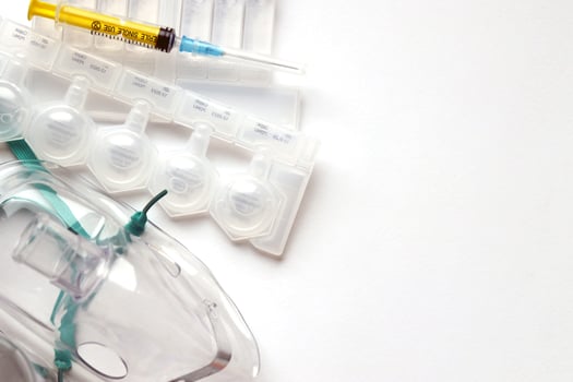 Coronavirus treatment concept. A medical face mask nebulizer for treatment of respiratory tract and packs of ampoules flat layed on a white background photo