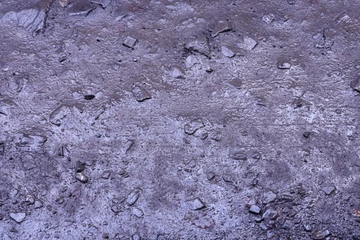 Close up of muddy puddle with small stones on wet surface. Background texture with top view photo