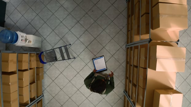 Top down view of african american inspector examining cardboard box parcels for damages in warehouse. Storage facility manager making sure stocks and inventory are well organized photo