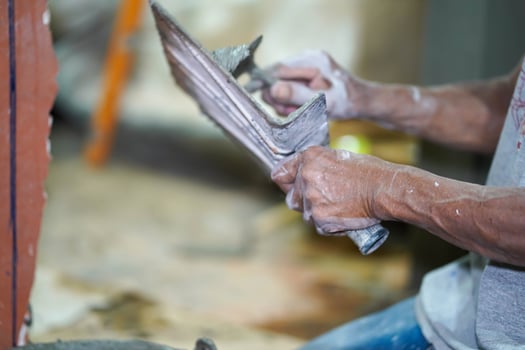 Closeup hands of builder holding mortar pan for plastering walls with cement in construction site photo