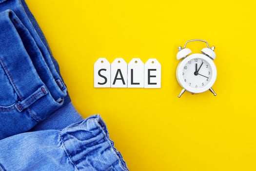 Flat lay, detail of jeans, white labels and inscription Sale on yellow background. photo