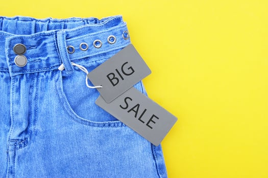 Flat lay, detail of denim jeans with gray label and inscription BIG SALE on yellow background. photo