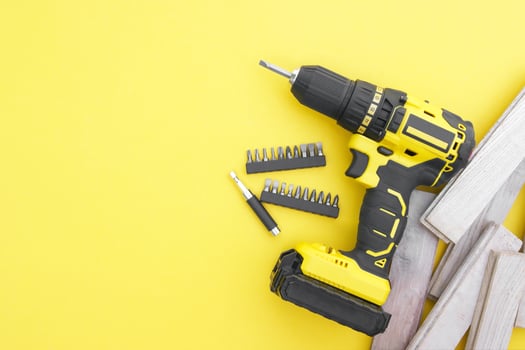 The yellow-black screwdriver on a yellow background, screws, a set of bits. photo