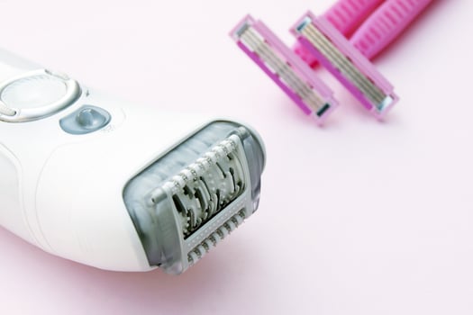 White epilator and pink razor on a pink background. photo