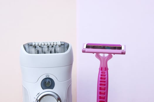 White epilator and pink razor on a pink background. photo