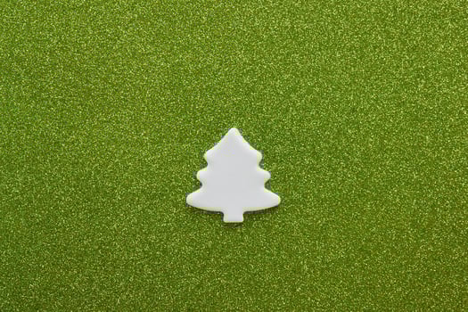 White carved christmas tree of mastic on green background. photo