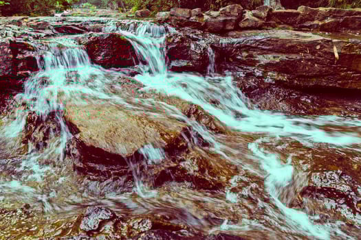 A man is sitting on a rock in a stream photo