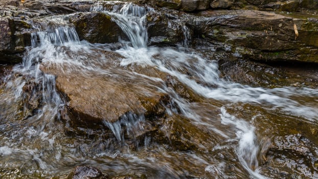 A stream of water flows over rocks in a rocky area photo