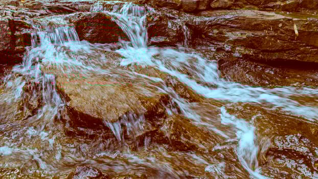 A man is standing on a rock in a stream photo