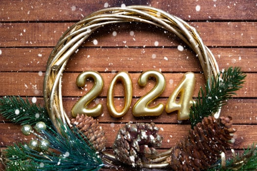 Happy New Year wooden numbers 2024 on cozy festive brown wooden background with sequins, snow, lights of garlands. Greetings, postcard. Calendar, cover photo