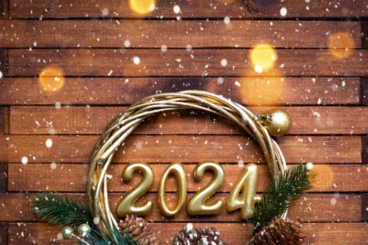Happy New Year wooden numbers 2024 on cozy festive brown wooden background with sequins, snow, lights of garlands. Greetings, postcard. Calendar, cover photo