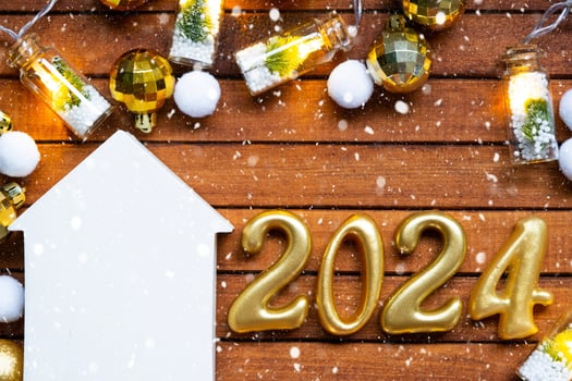 House key with tiny figure of home mock up on festive brown wooden background, lights of garlands. New Year 2024 wooden letters, greeting card. Purchase, construction, relocation, mortgage, insurance photo