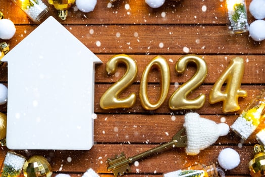 House key with tiny figure of home mock up on festive brown wooden background, lights of garlands. New Year 2024 wooden letters, greeting card. Purchase, construction, relocation, mortgage, insurance photo