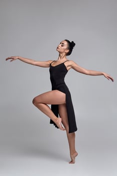 Dancing ballerina in a black dress. Contemporary graceful performance on a gray background. photo