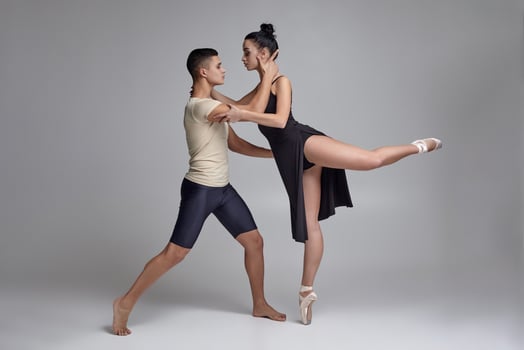 Two athletic modern ballet dancers are posing against a gray studio background. photo
