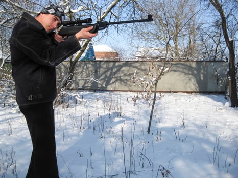 man with an air rifle in a winter park. photo