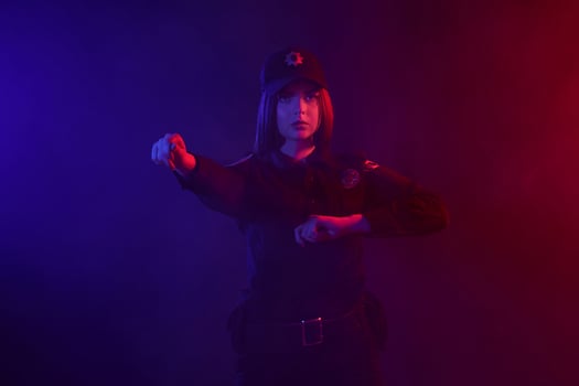 Redheaded female police officer is posing for the camera against a black background with red and blue backlighting. photo