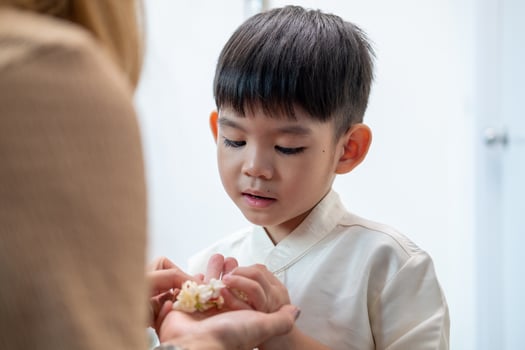 Little asian boy Giving a jasmine garland to mother On Thailand's National Mother's Day photo