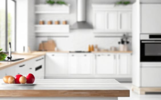 Blurred view of modern kitchen with white furniture with wooden table photo