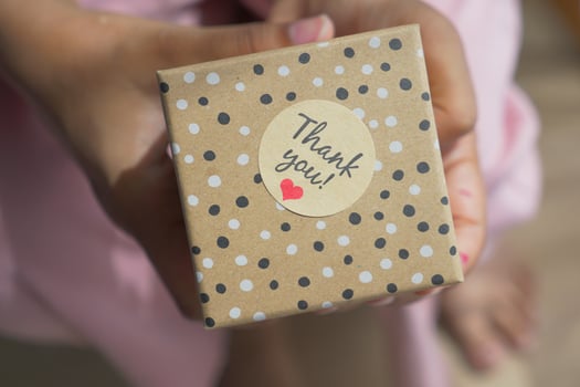 hand putting a thank you sticker on a gift box photo