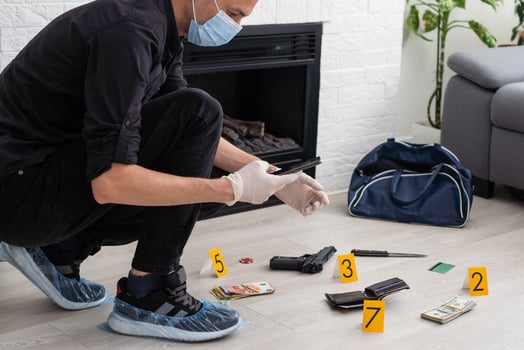 Young policeman collecting evidence standing behhind yellow crime scene tape photo