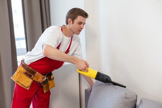 Rear View Of Young Male Worker Cleaning Sofa With Vacuum Cleaner photo