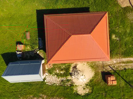 House with an orange roof made of metal, top view. Metallic profile painted corrugated on the roof. photo