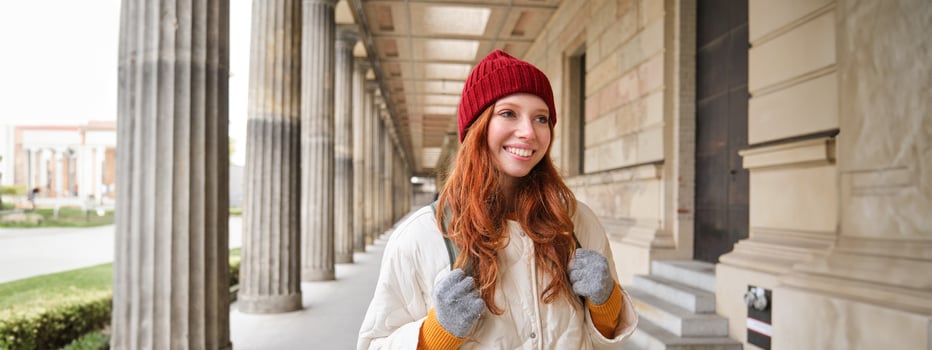 Happy girl traveller with red long hair, walking in city, sightseeing, backpacking around europe in winter photo